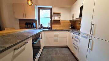A modern kitchen with white cabinets, a built-in oven, and a coffee maker.