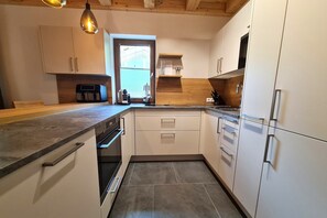 A modern kitchen with white cabinets, a built-in oven, and a coffee maker.