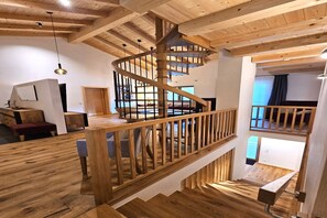 A wooden interior with a spiral staircase, wooden floors, and a view of a balcony.