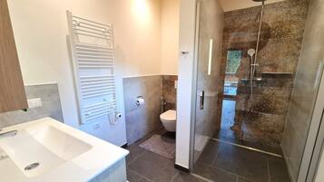 Een moderne badkamer met douche, toilet en wastafel.