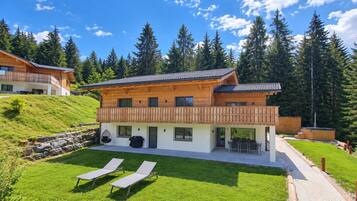 Eine moderne Holzchalet mit Balkon, einer Terrasse mit Gartenmöbeln und einem gepflegten Rasen.