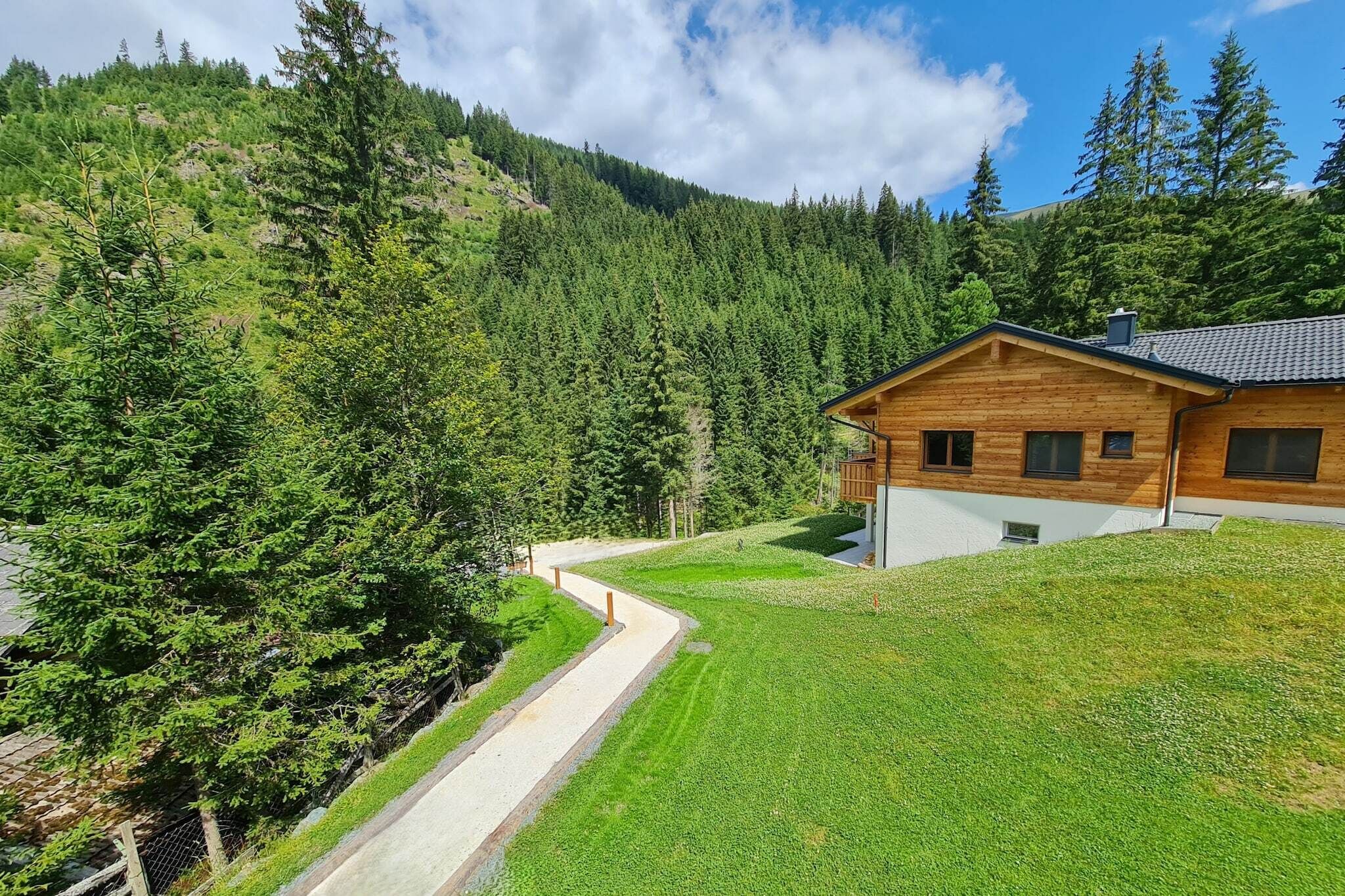 Eine Holzhütte mit geneigtem Dach, umgeben von einem gepflegten Rasen und dichtem Wald.