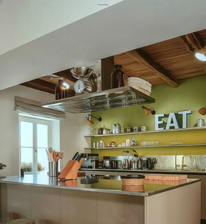 A modern kitchen with a central island, wooden ceiling beams, and a large 'EAT' sign on the wall. - Villa with Pool near Motovun in Istrian Village (Prašćari)