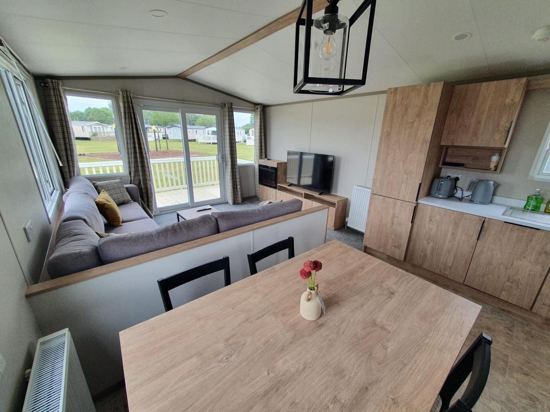 A compact living space with a sofa, a dining table, a TV, and a kitchenette.