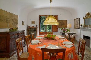 Ein Esszimmer mit einem runden Tisch, gedeckt für vier Personen, umgeben von Holzstühlen.