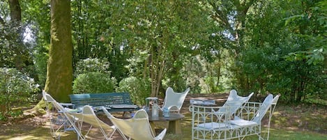 An outdoor seating area with a table and chairs, surrounded by trees.