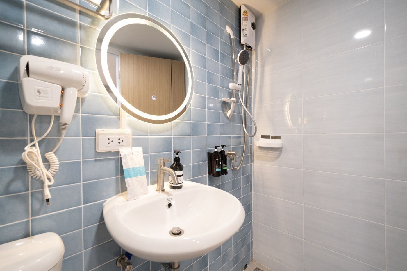 A bathroom with a white sink, a mirror, a hairdryer, and a shower.