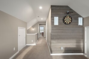 Ein Flur mit einer Wand in Holzoptik, einem Dartboard und einem Punktezettel.