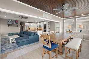 Eine moderne Küche mit weißen Schränken, einem Holzesstisch und einem Deckenventilator.