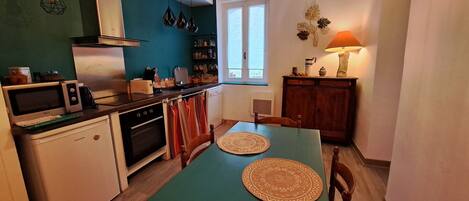 A compact kitchen with a dining table, a refrigerator, an oven, and a microwave.