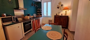 A compact kitchen with a dining table, a refrigerator, an oven, and a microwave. - Apartment within the fortified walls, 3-star (Villefranche-de-Conflent)