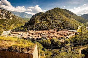 A town nestled in a valley with a prominent hill, surrounded by greenery and a clear sky. - Apartment within the fortified walls, 3-star (Villefranche-de-Conflent)