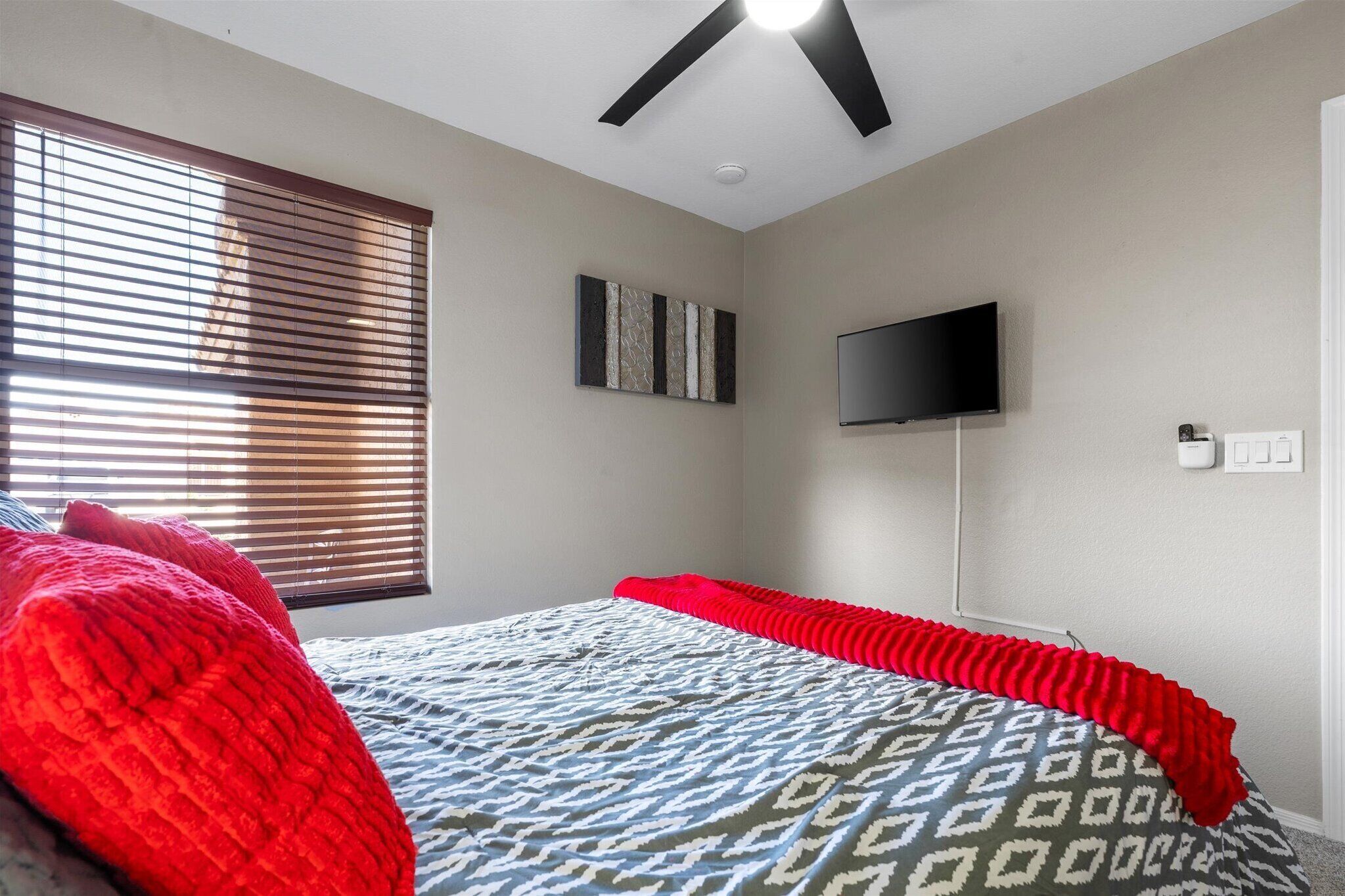 Queen bedroom with TV, ceiling fan, and natural light provides a comfortable retreat at the end of the day.