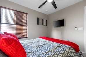 Queen bedroom with TV, ceiling fan, and natural light provides a comfortable retreat at the end of the day.