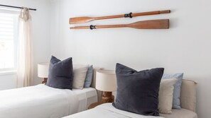 A hotel room with two beds, a window with curtains, and two wooden paddles mounted on the wall. - The Lodge, Noosa - Stylish Retreat with Pool (Noosa Heads)