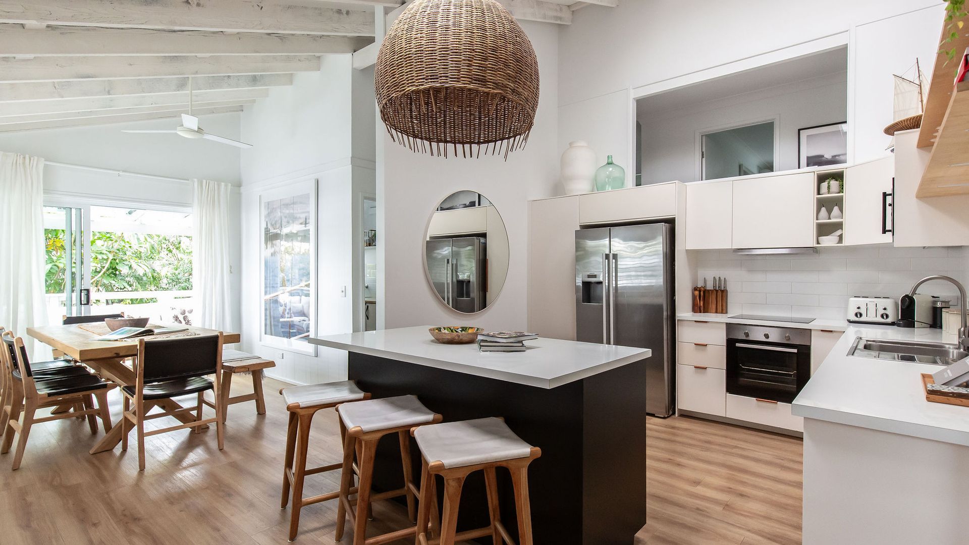 A modern kitchen with white cabinetry, a central island, and a large woven pendant light.