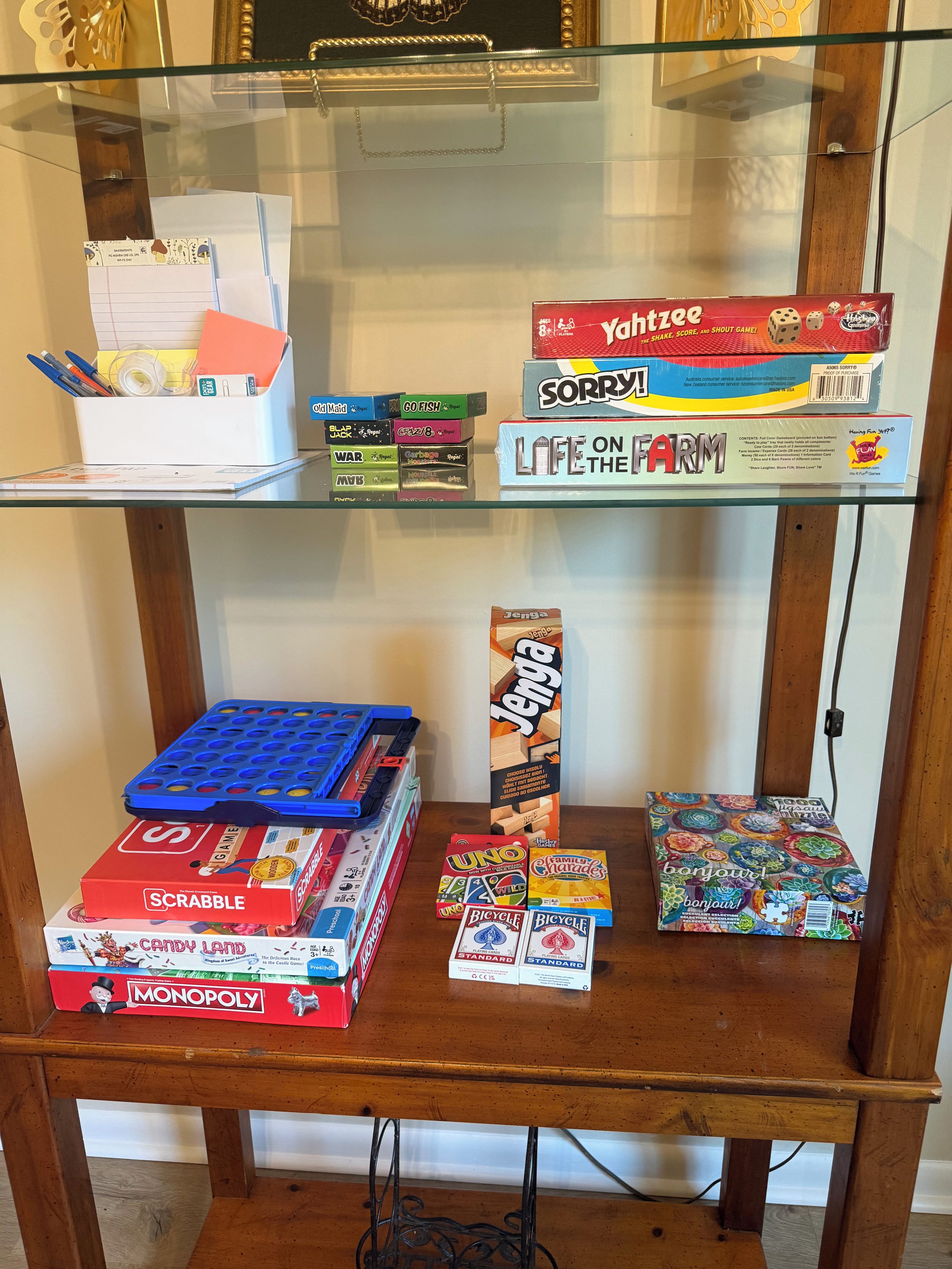 A glass display case with various board games and a blue tray on a wooden table.