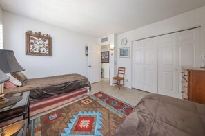 A bedroom with a bed, a chair, a desk, a lamp, and a wardrobe. - Dramatic end unit 2 bedrm split floor plan   B26 Great central location (Tucson)