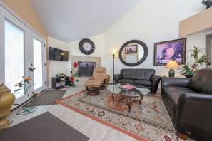 A living room with a sofa, armchairs, a coffee table, a TV, and a fireplace. - Dramatic end unit 2 bedrm split floor plan   B26 Great central location (Tucson)