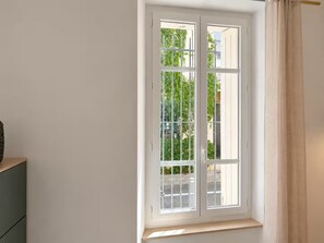 A room with a window overlooking a street, a wooden bench, and a green cabinet. - Hypercenter • Le Cornue • air-conditioned with a patio (Avignon)