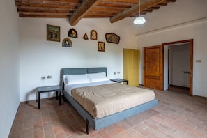 Una camera da letto con un letto, due comodini, un soffitto in legno e una porta.