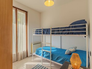 Ein Schlafraum mit Etagenbetten, einem Heizkörper, einem Schreibtisch und einer Lampe.