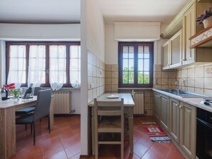 Eine Küche mit Essbereich, Heizkörper, Fenster mit Aussicht und gefliestem Spritzschutz.