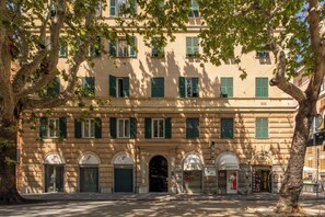 Ein mehrstöckiges Gebäude mit Rundbogenfenstern und grünen Fensterläden, mit einem 'LOTTO 109' Schild.