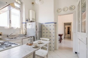 Eine Küche mit Gasherd, Kühlschrank, Spüle und einem Esstisch mit Stühlen.