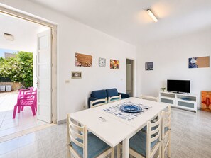 Ein modernes Wohnzimmer mit Esstisch, Stühlen, einer Couch, einem Fernseher und Kunstwerken an den Wänden.