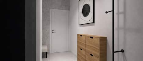 A hallway with a white door, a bench, a wooden cabinet, and a wall-mounted rack.