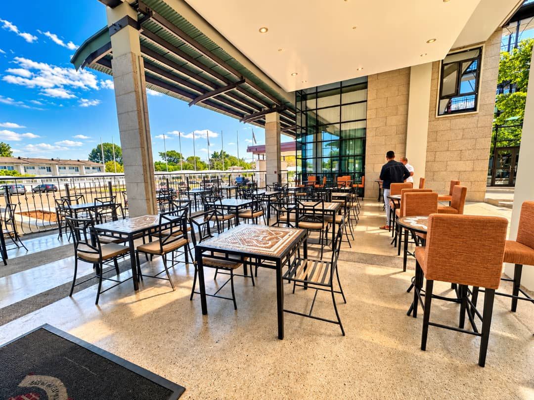 An outdoor cafe with tables and chairs, a covered seating area, and a view of the surrounding area.