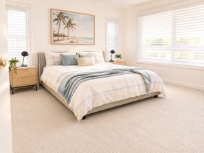 A bedroom with a bed, two bedside tables, a nightstand, a window with blinds, and a painting on the wall. - Palm Springs Family Home – Gym, Garage, Pets, 10 minutes drive from Manly beach (North Balgowlah)