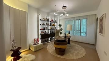 Uma sala de estar moderna com uma mesa de centro redonda, uma estante e uma grande janela com cortinas.