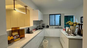 Cozinha moderna com armários brancos, uma ilha central e uma janela que traz luz natural.