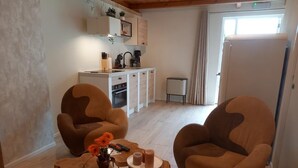 A living room with two brown armchairs, a coffee table, and a small side table with a vase of flowers. - Pura Vida Suite: Enjoy Life! (Oud Ade)