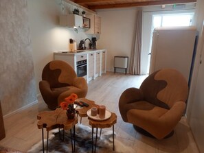 Ein Wohnzimmer mit zwei braunen Sesseln, einem Couchtisch und einem kleinen Beistelltisch mit einer Blumenvase.