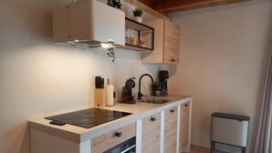 A compact kitchen with a built-in stove, a sink, and a small trash bin. - Pura Vida Suite: Enjoy Life! (Oud Ade)