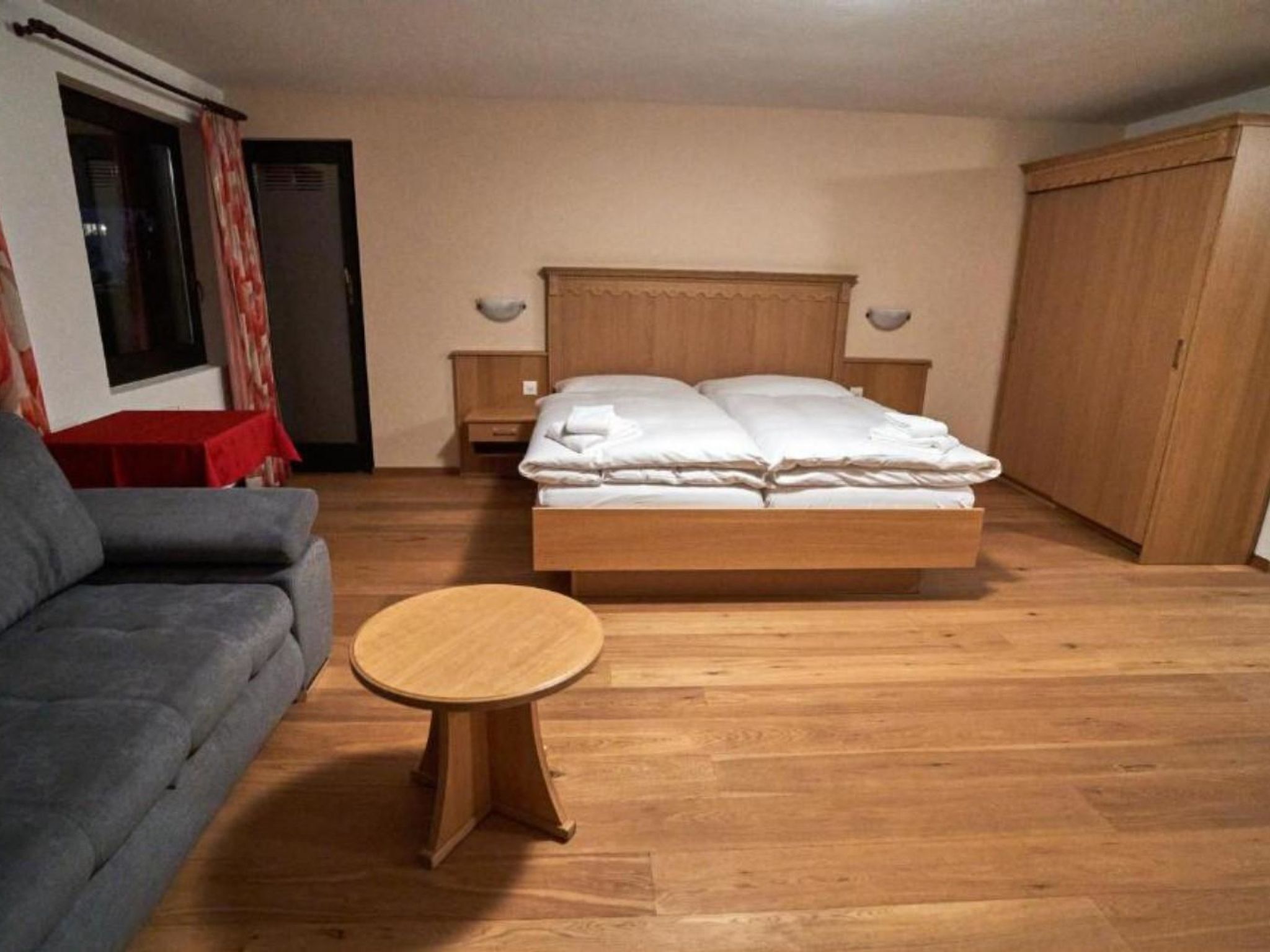 Ein Schlafzimmer mit einem Bett, einem Schlafsofa, einem kleinen Tisch und einem Kleiderschrank.