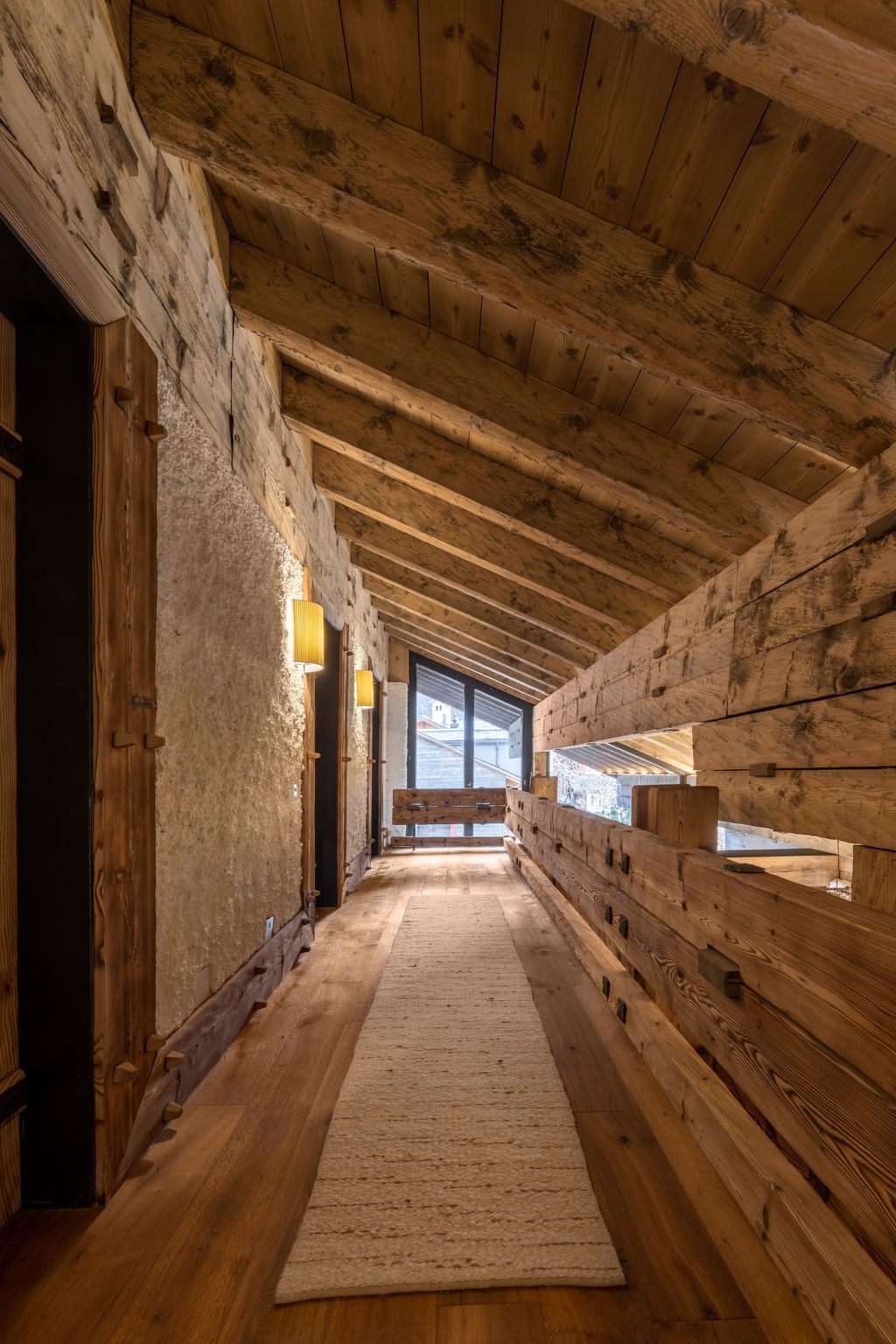 Un pasillo interior de madera con alfombra, paredes de madera y un banco.