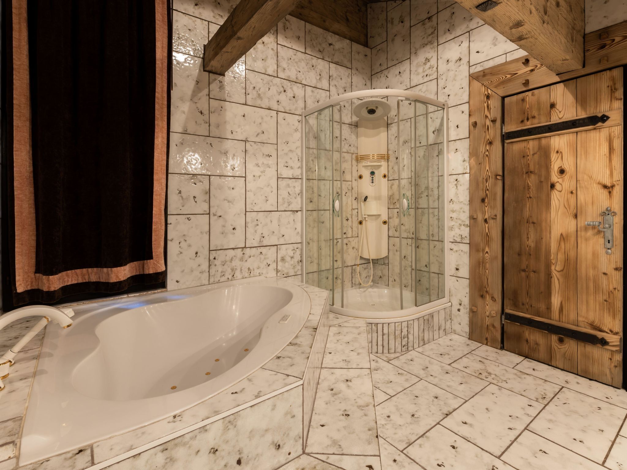 Ein Badezimmer mit einer freistehenden Badewanne, einer gläsernen Dusche und einer Holztür.