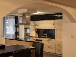 Eine moderne Küche mit einer zentralen Kochinsel, Edelstahlgeräten und Holzschränken.