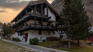 A multi-story building with a balcony, surrounded by trees and a mountain backdrop. - Villa Alpenhof Appartement/Fewo Wohnung für 6 Personen by Interhome (Saas-Almagell)