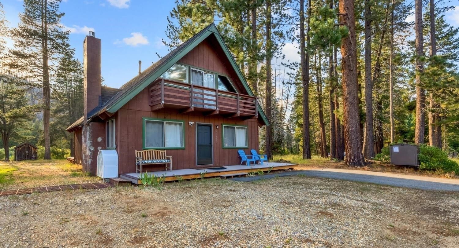 A cabin with a balcony, a bench, and a chair outside.