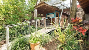 A wooden house with a blue door, a metal staircase, and a garden with various plants.