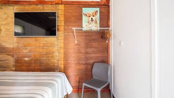Una habitación de cabaña de madera con una cama, una silla, un cuadro y una ventana.