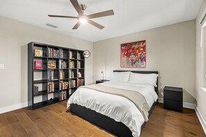 A bedroom with a bed, a bookshelf, a ceiling fan, a wall art piece, and a nightstand. - Arlington Park Oasis 4 Bedroom Home (Sarasota)