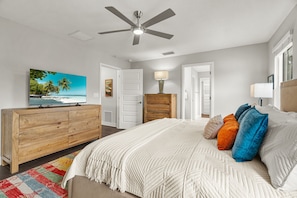 A bedroom with a bed, a television, a ceiling fan, and a view of the outdoors. - Arlington Park Oasis 4 Bedroom Home (Sarasota)