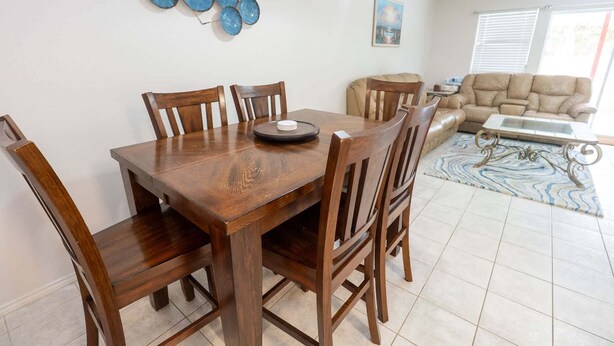 Een eethoek met een houten tafel en stoelen, een decoratief bord, een bank en een tapijt met een patroon.
