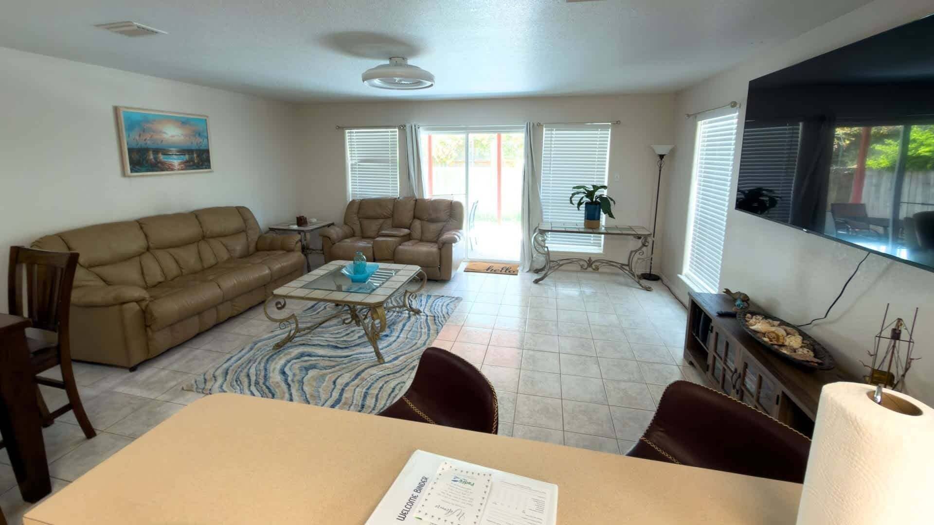 A living room with a sofa, armchairs, a coffee table, and a dining table.